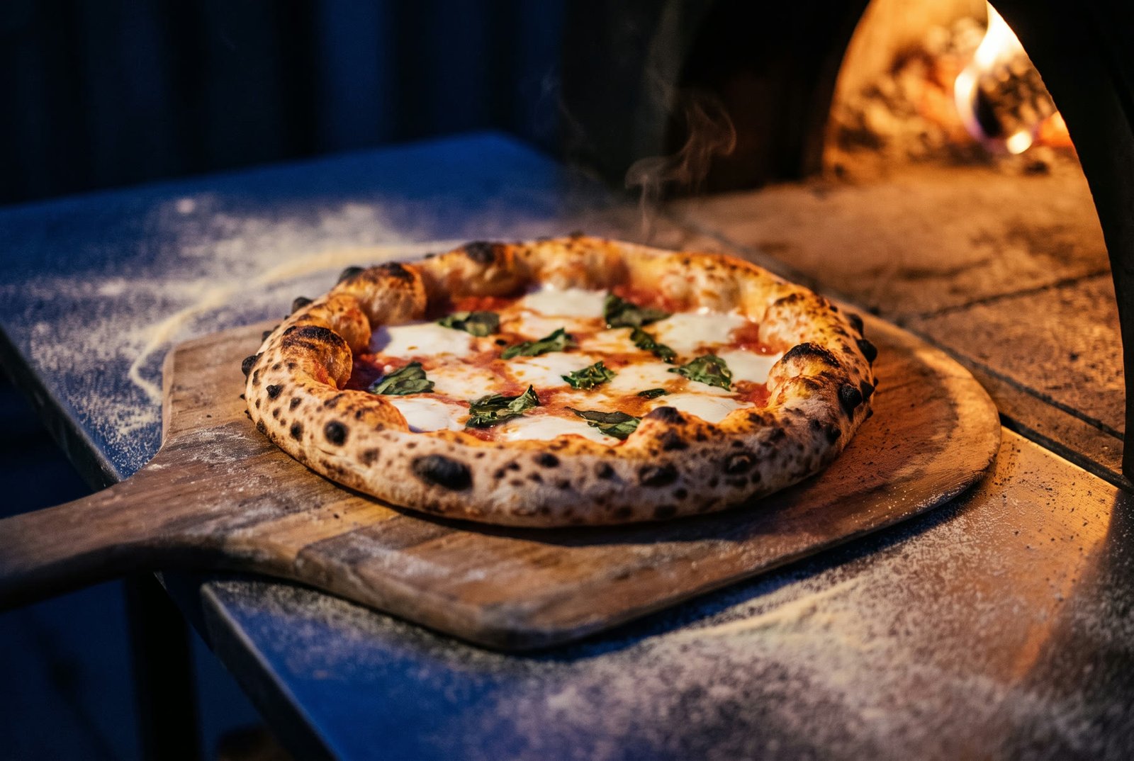 Pizza margarita recién salida del horno de leña sobre una pala de madera.